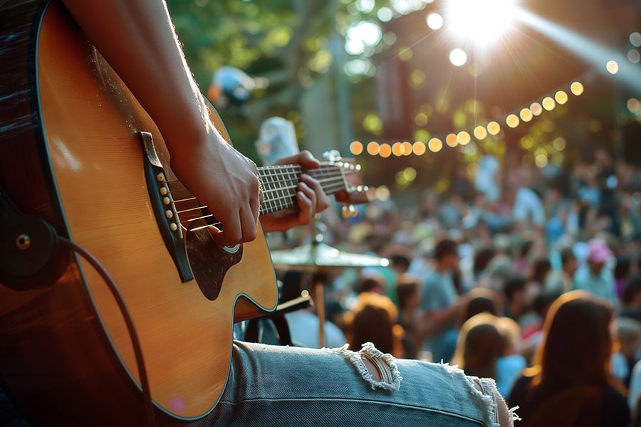 Close-up of musician playing acoustic guitar on stage during liv